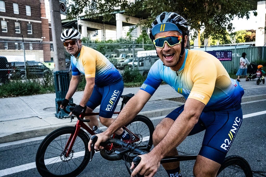 two cyclists riding on a street smiling for a picture