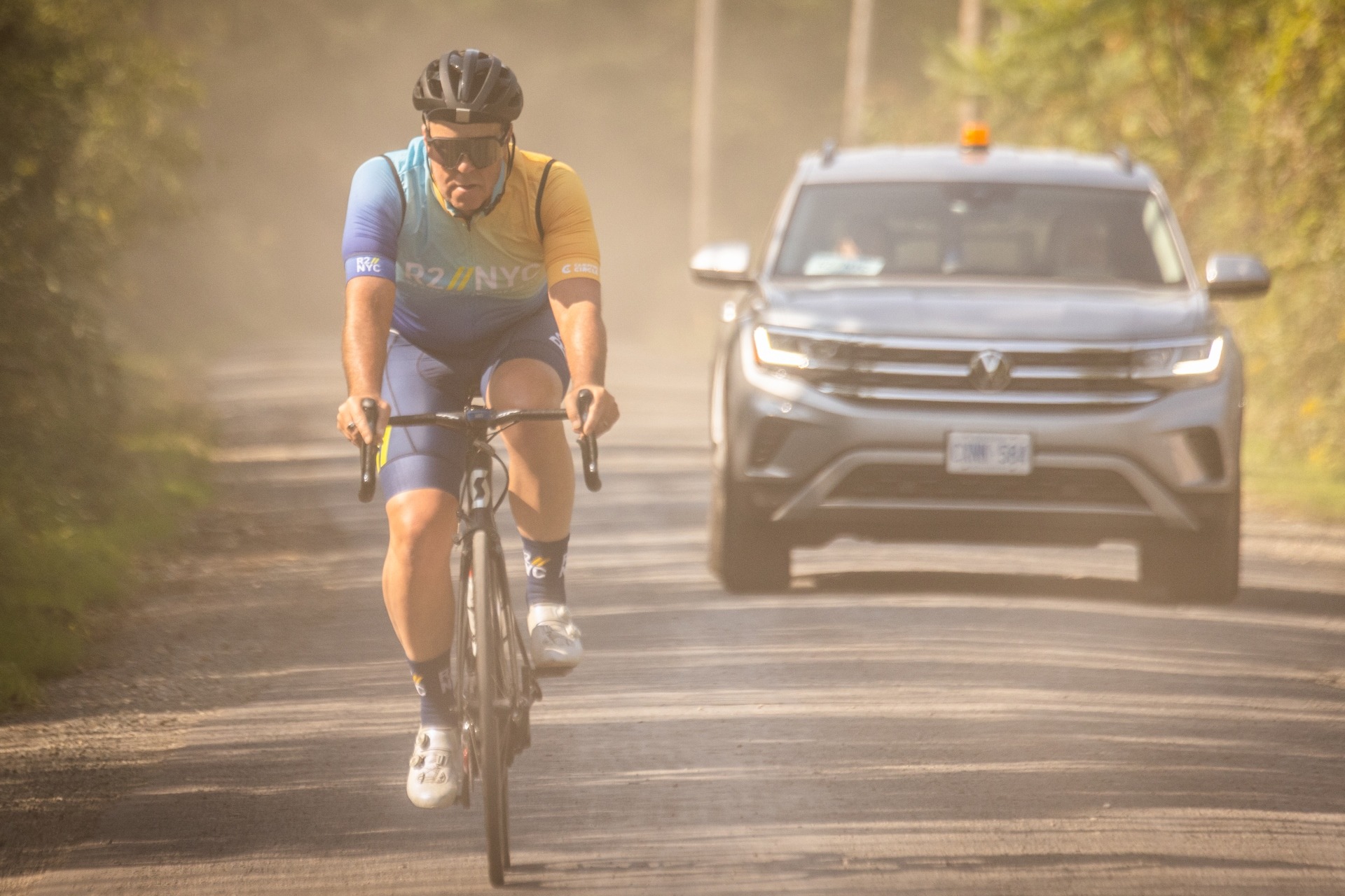 cyclist riding on a dusty road in front of Volkswagen support day