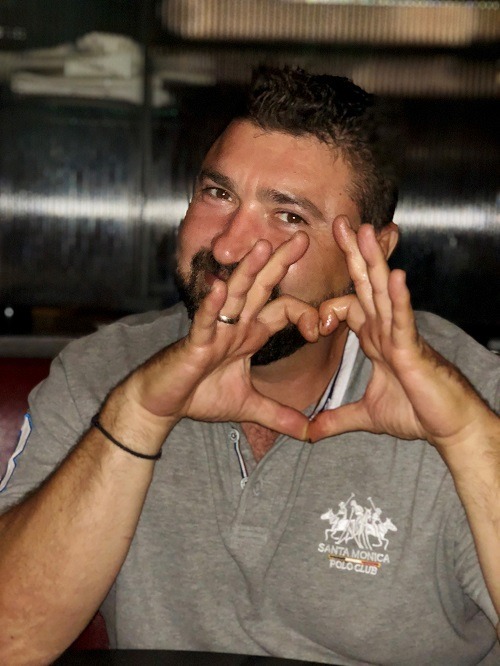 Trifon smiling at camera with his hands up