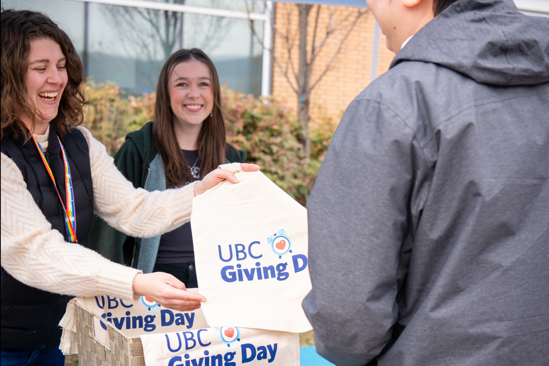 Two volunteers handing out tote bags at UBC Giving Day event.
